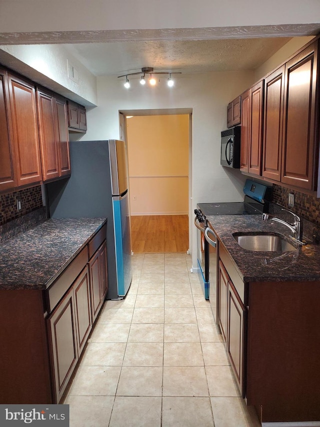 kitchen featuring range with electric cooktop, light tile patterned flooring, sink, dark stone countertops, and backsplash