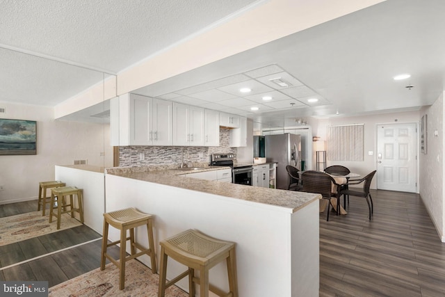 kitchen featuring a kitchen bar, sink, white cabinetry, appliances with stainless steel finishes, and kitchen peninsula