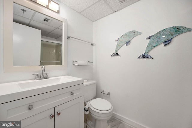 bathroom with vanity, a paneled ceiling, a shower with door, and toilet