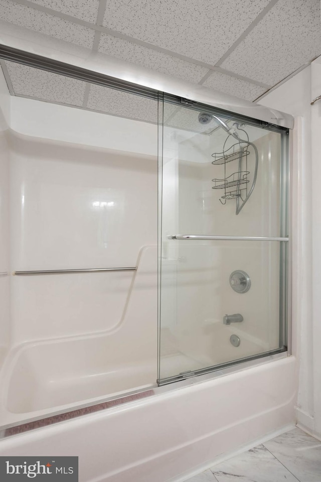 bathroom with a drop ceiling and combined bath / shower with glass door