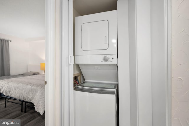 washroom with dark hardwood / wood-style floors and stacked washing maching and dryer