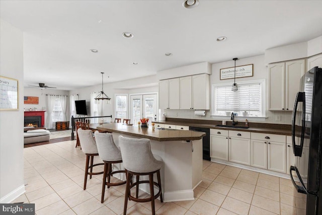 kitchen with white cabinets, open floor plan, black appliances, dark countertops, and pendant lighting