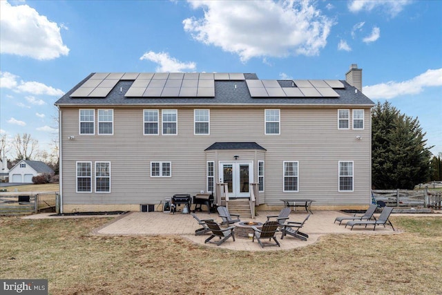 rear view of house with an outdoor fire pit, fence, a yard, a patio area, and roof mounted solar panels