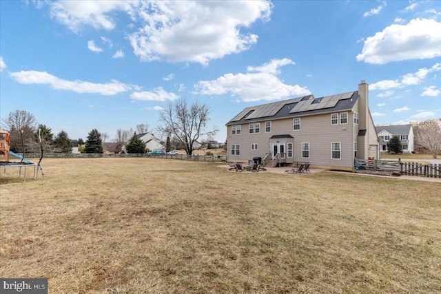 back of property featuring solar panels, a chimney, fence, a patio area, and a playground