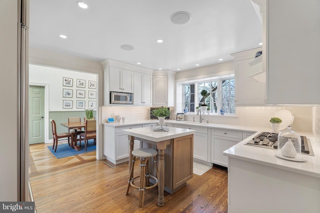 kitchen featuring appliances with stainless steel finishes, a kitchen breakfast bar, white cabinets, a kitchen island, and sink