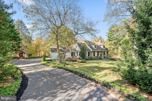 new england style home with a storage unit and a front yard