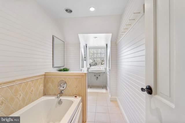 bathroom with a tub, tile walls, and tile patterned flooring