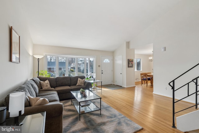 living room featuring vaulted ceiling, an inviting chandelier, and hardwood / wood-style floors