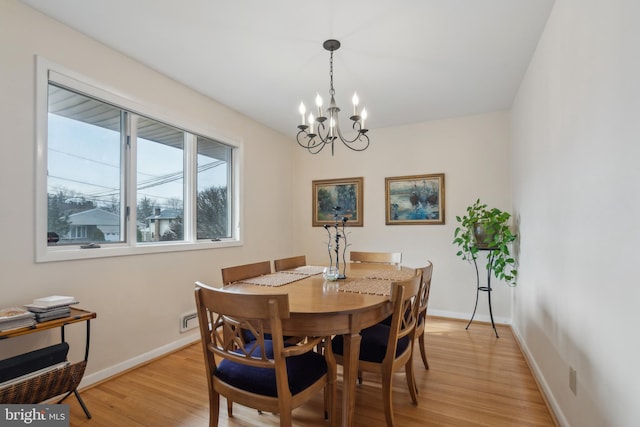 dining area with an inviting chandelier and light hardwood / wood-style flooring