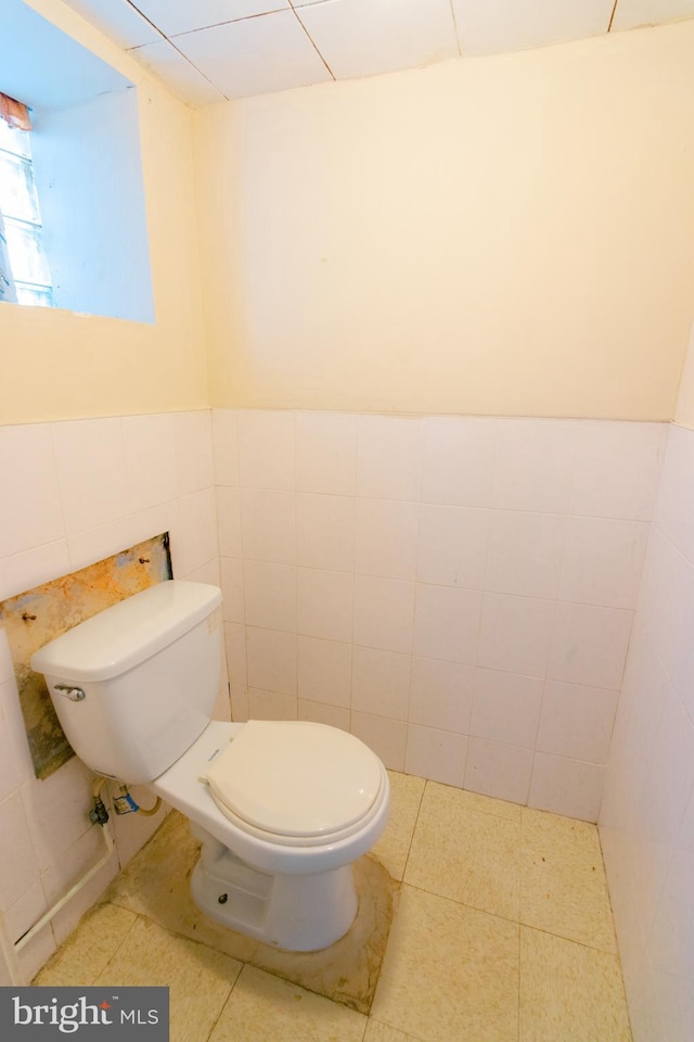 bathroom with tile walls, tile patterned floors, and toilet