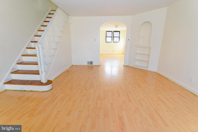 spare room with built in shelves and light hardwood / wood-style floors