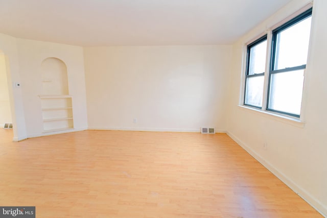 unfurnished room with light hardwood / wood-style floors and built in shelves