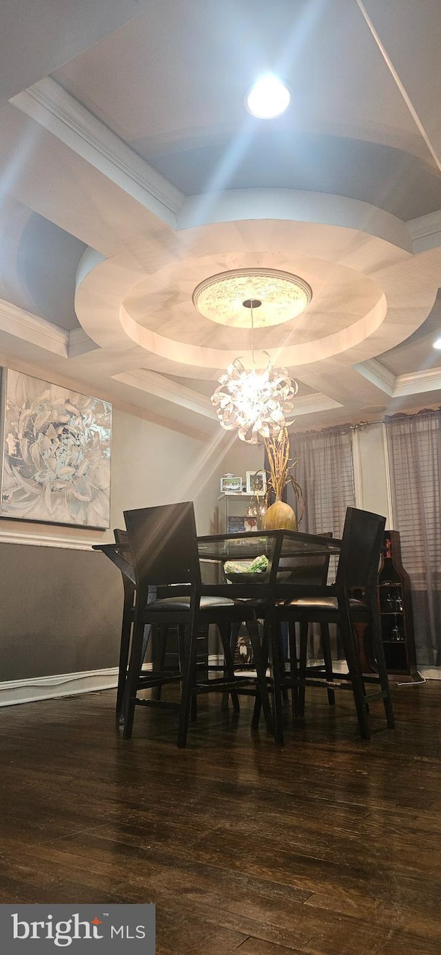 dining area featuring a raised ceiling, dark hardwood / wood-style flooring, crown molding, and an inviting chandelier