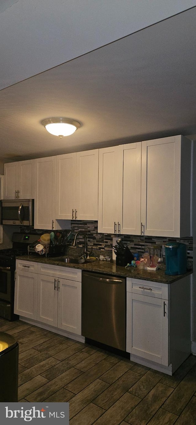 kitchen featuring stainless steel appliances, white cabinetry, sink, and dark hardwood / wood-style floors