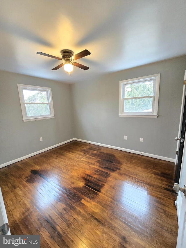 unfurnished room with dark wood-type flooring, ceiling fan, and a wealth of natural light