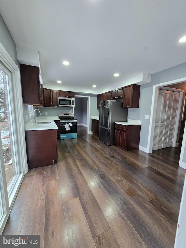 kitchen featuring appliances with stainless steel finishes, sink, dark hardwood / wood-style floors, and dark brown cabinets