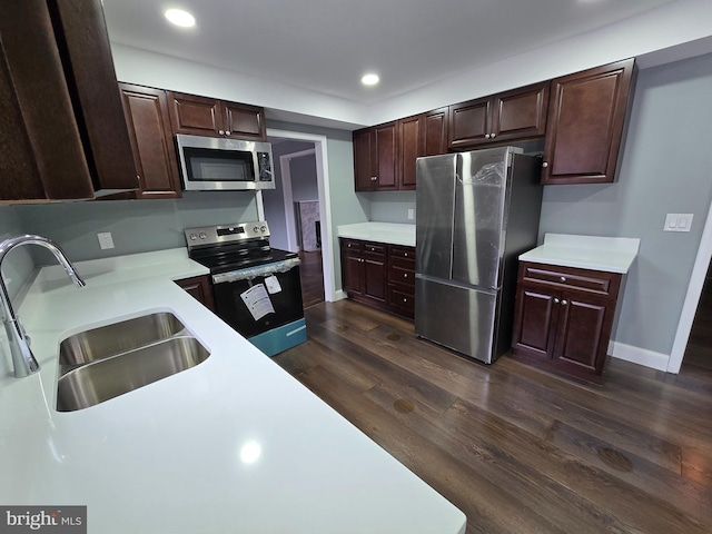 kitchen with dark brown cabinetry, stainless steel appliances, dark hardwood / wood-style floors, and sink