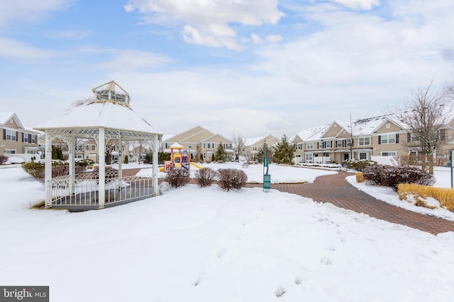 yard layered in snow featuring a gazebo and a playground