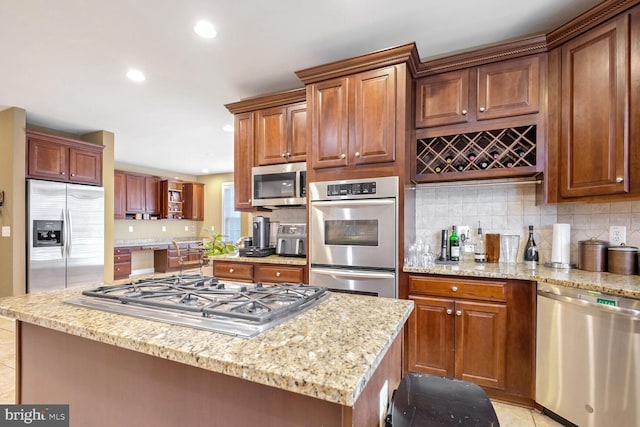 kitchen featuring light tile patterned floors, appliances with stainless steel finishes, tasteful backsplash, light stone counters, and a kitchen island