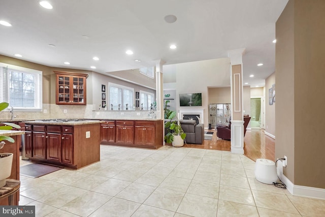 kitchen with light stone counters, light tile patterned floors, decorative backsplash, and decorative columns