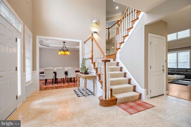 foyer with an inviting chandelier, light tile patterned flooring, and a high ceiling