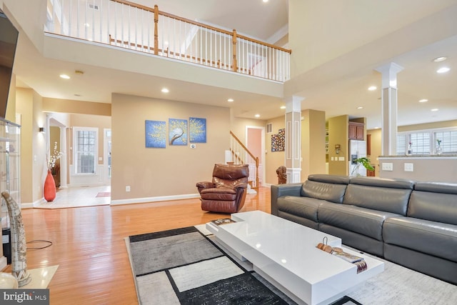 living room with ornate columns, a high ceiling, a wealth of natural light, and light hardwood / wood-style floors