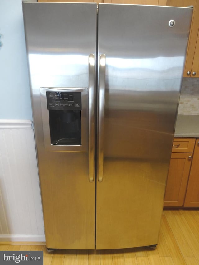 room details featuring tasteful backsplash, stainless steel fridge, and light hardwood / wood-style floors