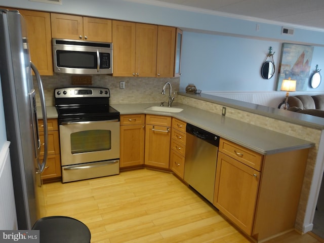 kitchen with sink, stainless steel appliances, light hardwood / wood-style floors, ornamental molding, and kitchen peninsula