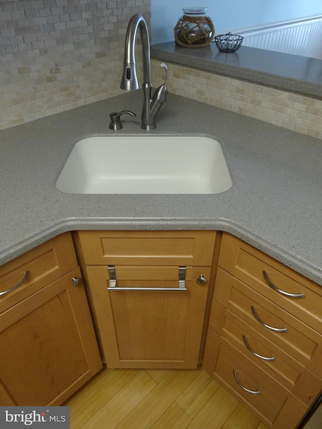 details with tasteful backsplash, sink, and light wood-type flooring