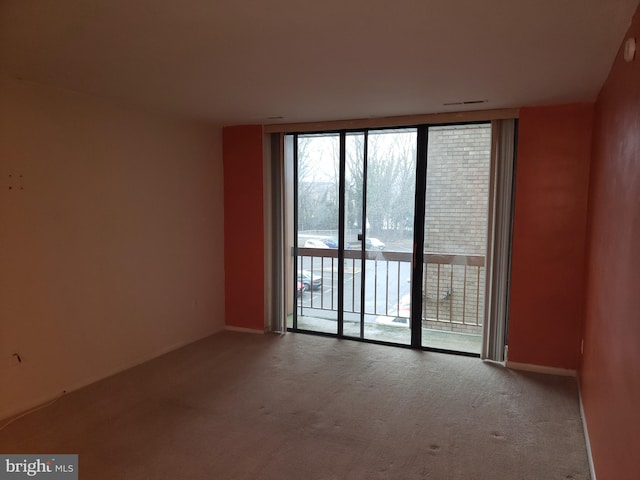 unfurnished room featuring a wall of windows and carpet flooring