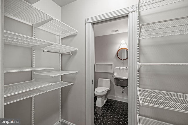 bathroom with toilet, baseboards, visible vents, and a sink