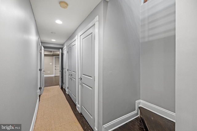 hallway with recessed lighting, dark wood-type flooring, and baseboards