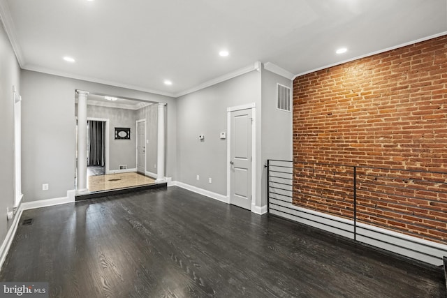 unfurnished living room featuring visible vents, brick wall, baseboards, and wood finished floors