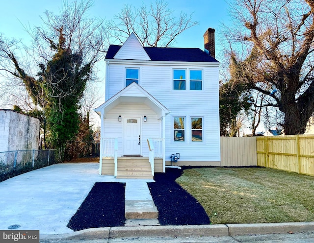 view of front of house featuring a chimney, a front yard, and fence