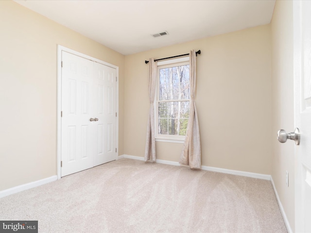 unfurnished bedroom featuring a closet and light colored carpet