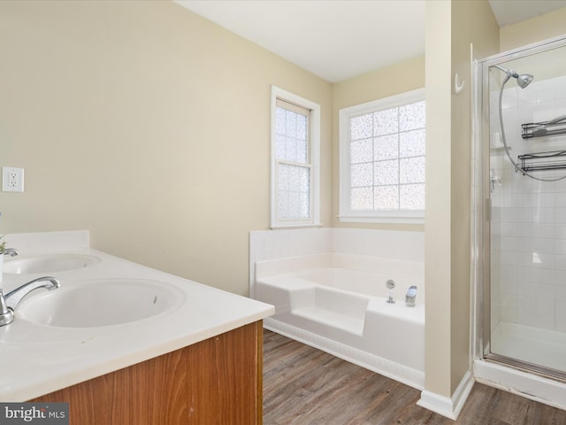 bathroom featuring plus walk in shower, vanity, and wood-type flooring