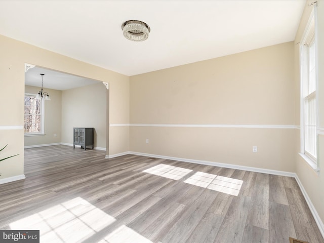 empty room featuring light hardwood / wood-style flooring and a chandelier