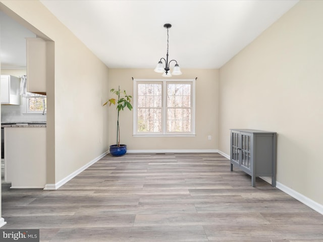 unfurnished dining area with light hardwood / wood-style floors and an inviting chandelier