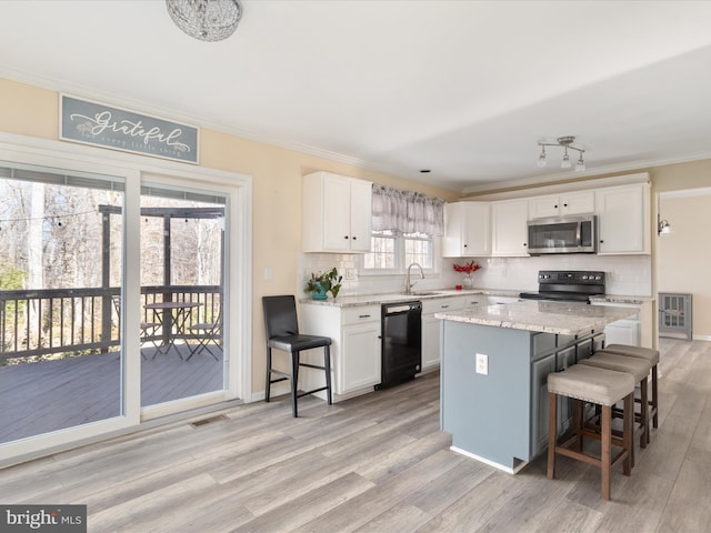 kitchen with white cabinetry, a breakfast bar, a kitchen island, black appliances, and sink