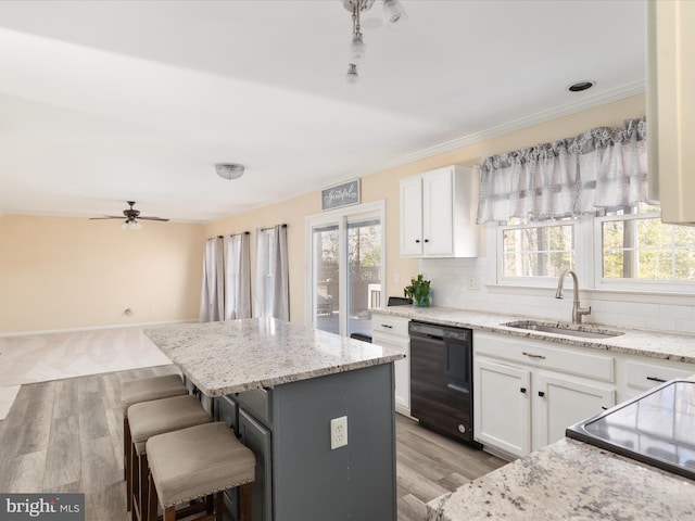 kitchen featuring a breakfast bar, black dishwasher, sink, a center island, and white cabinets