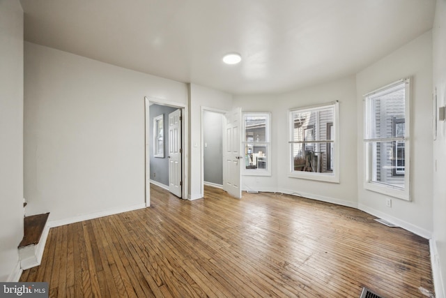 unfurnished living room featuring wood finished floors, visible vents, and baseboards