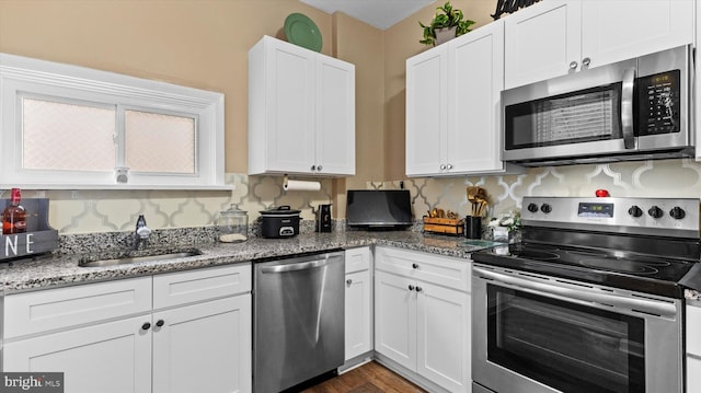 kitchen with sink, tasteful backsplash, appliances with stainless steel finishes, stone counters, and white cabinets