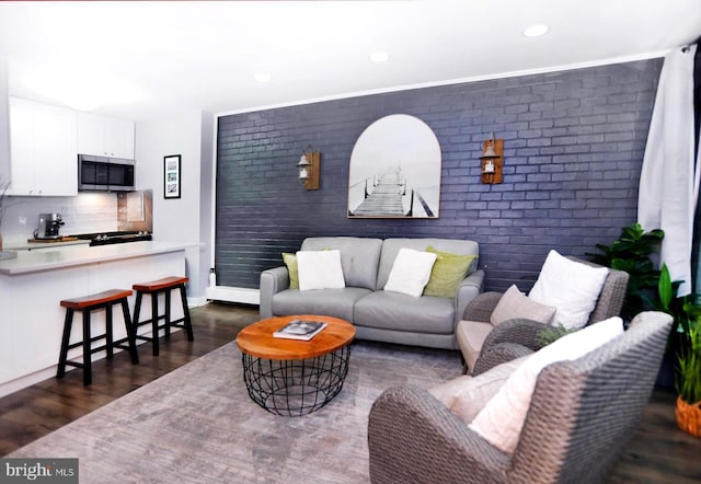 living room with brick wall and dark wood-type flooring