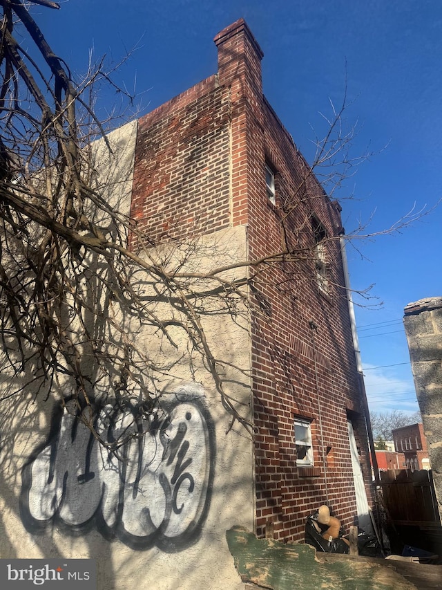 view of home's exterior with a chimney and brick siding