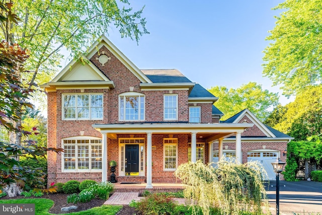 10002 Woodrow St, Vienna, VA 22181 - view of front of property featuring a garage, covered porch, driveway, and brick siding