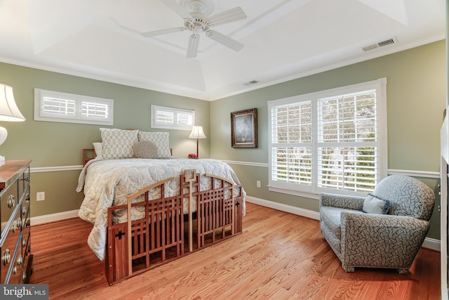 bedroom featuring a tray ceiling, wood finished floors, and visible vents