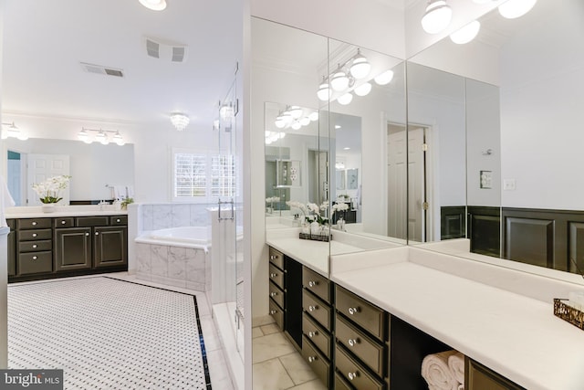 bathroom with vanity, ornamental molding, a bath, and visible vents