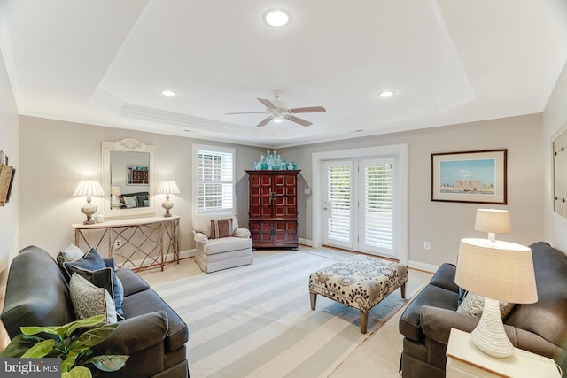 living room featuring ceiling fan, light colored carpet, baseboards, and a raised ceiling