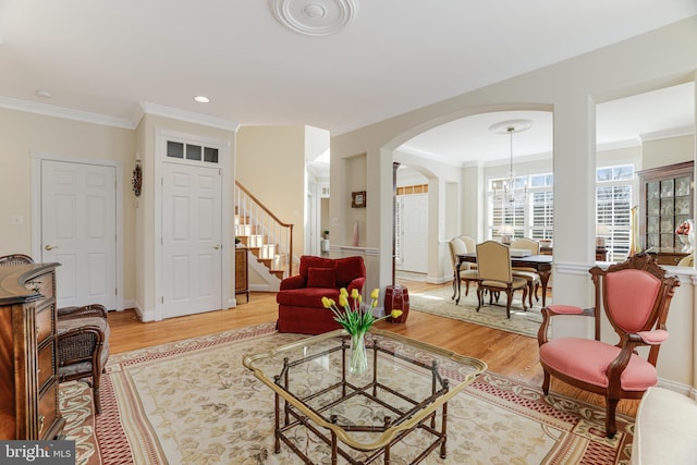 living area with arched walkways, stairs, light wood finished floors, ornamental molding, and recessed lighting
