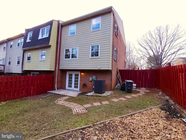 rear view of house with french doors, central AC, and a lawn